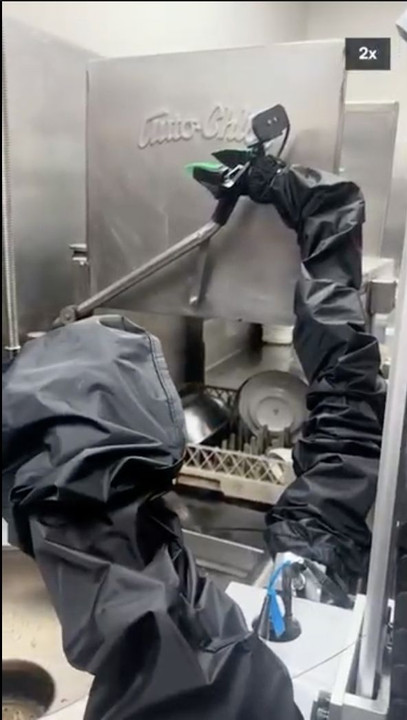 Robot arms reaching for the open door of a commercial dishwasher